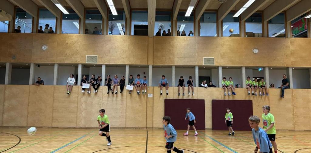Teamfoto Spielerinnen und Spieler in der Halle beim Fußballspielen beobachtet von Zusehern